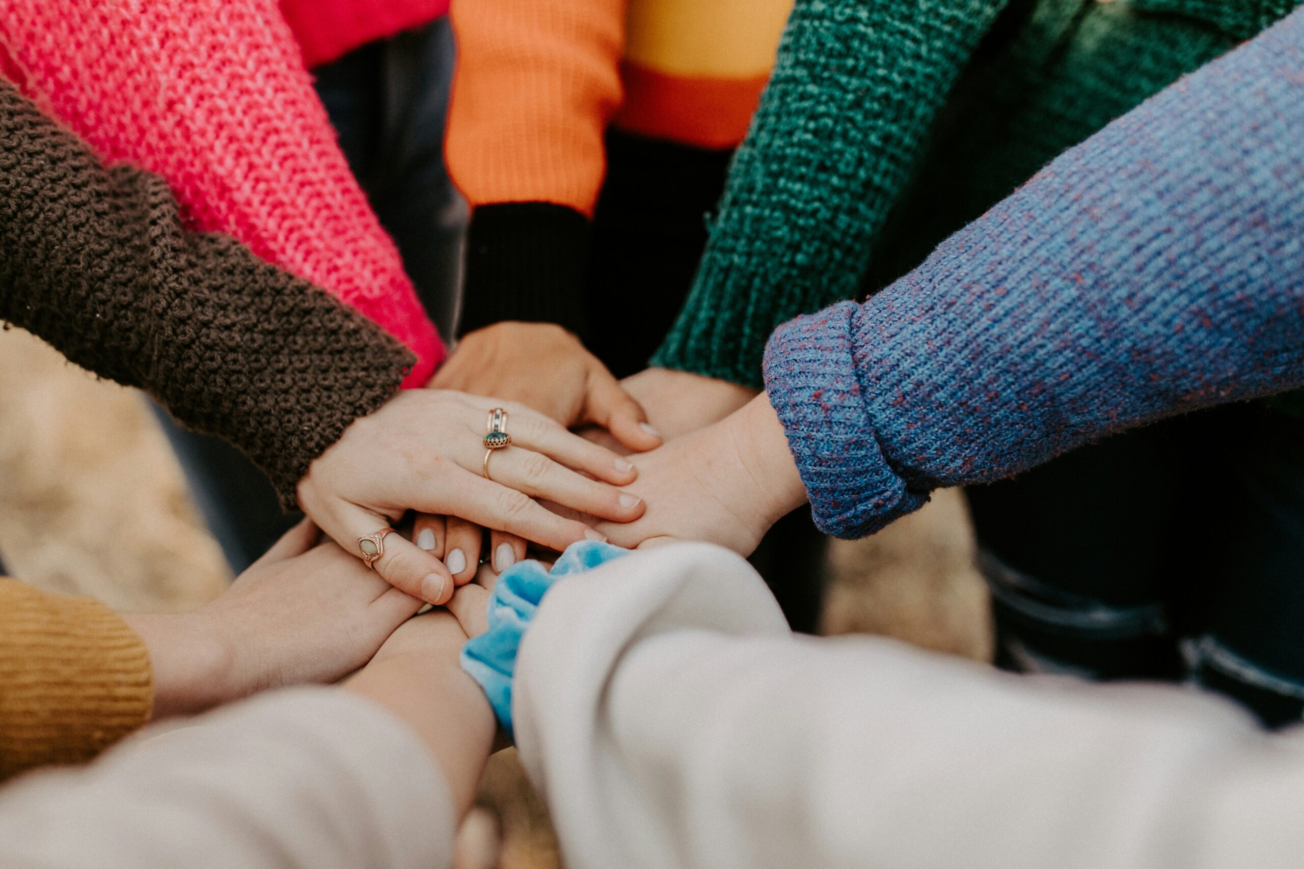 Persone che uniscono le mani al centro della foto a simboleggiare il lavoro di squadra. Foto di Hannah Busing su Unsplash