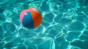 Acqua azzurra di una piscina e un pallone colorato che galleggia in solitudine. Foto di Raphaël Biscaldi su Unsplash